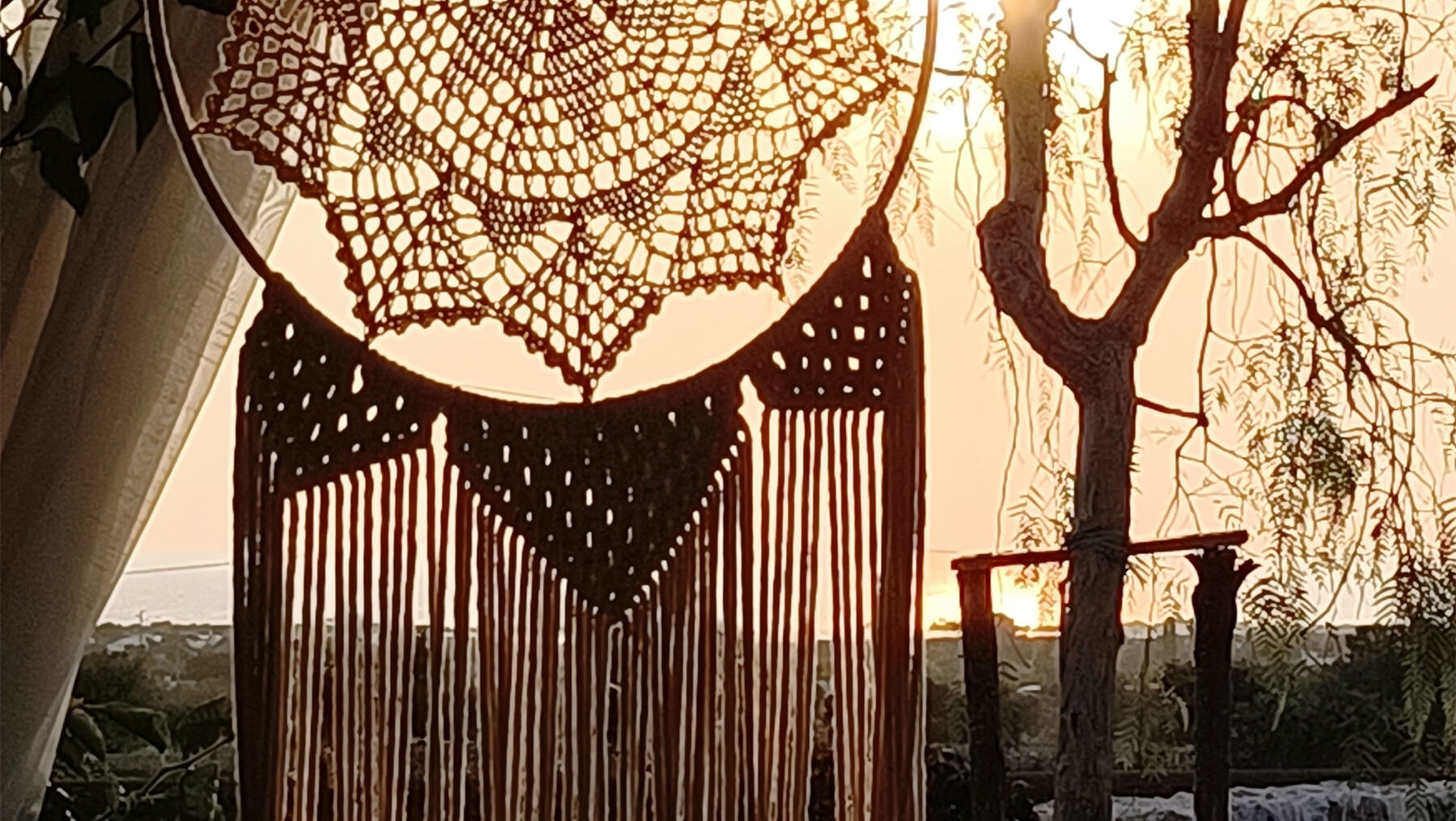 Tramonto a Bibiland visto attraverso un macramè, con il mare sullo sfondo