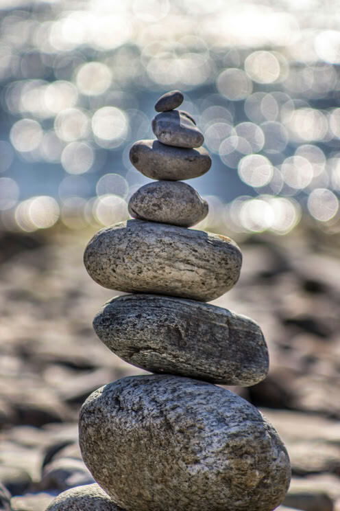 Balanced stones on the shore, with light reflecting on the water