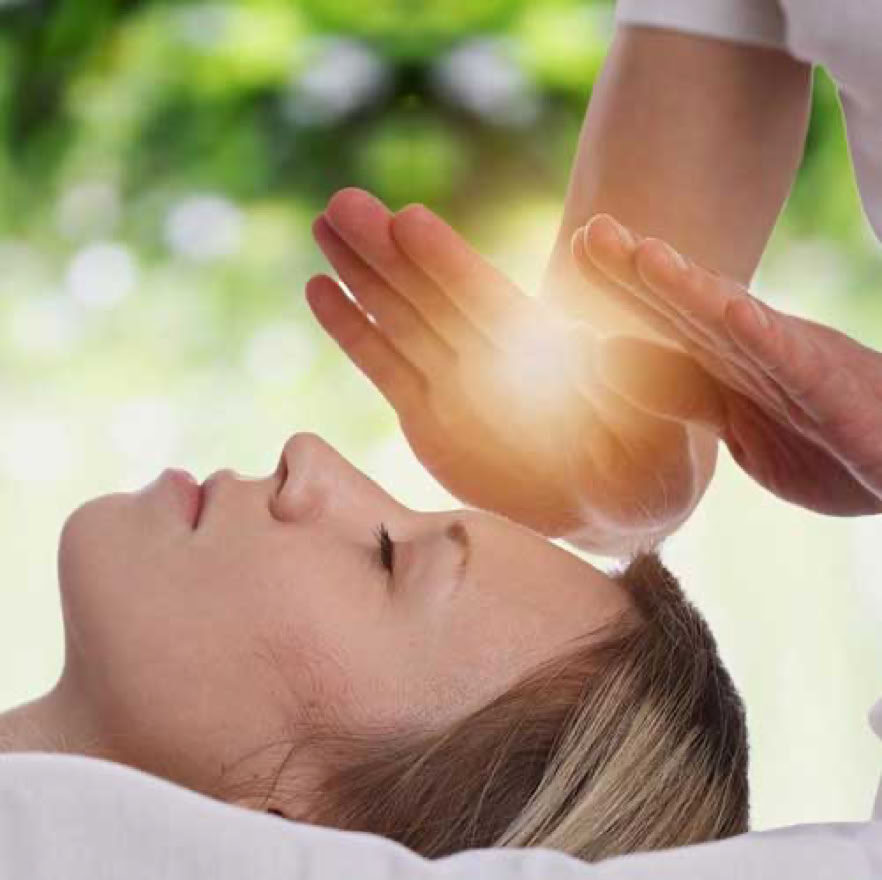 Hands transmitting light above the face of a person lying down