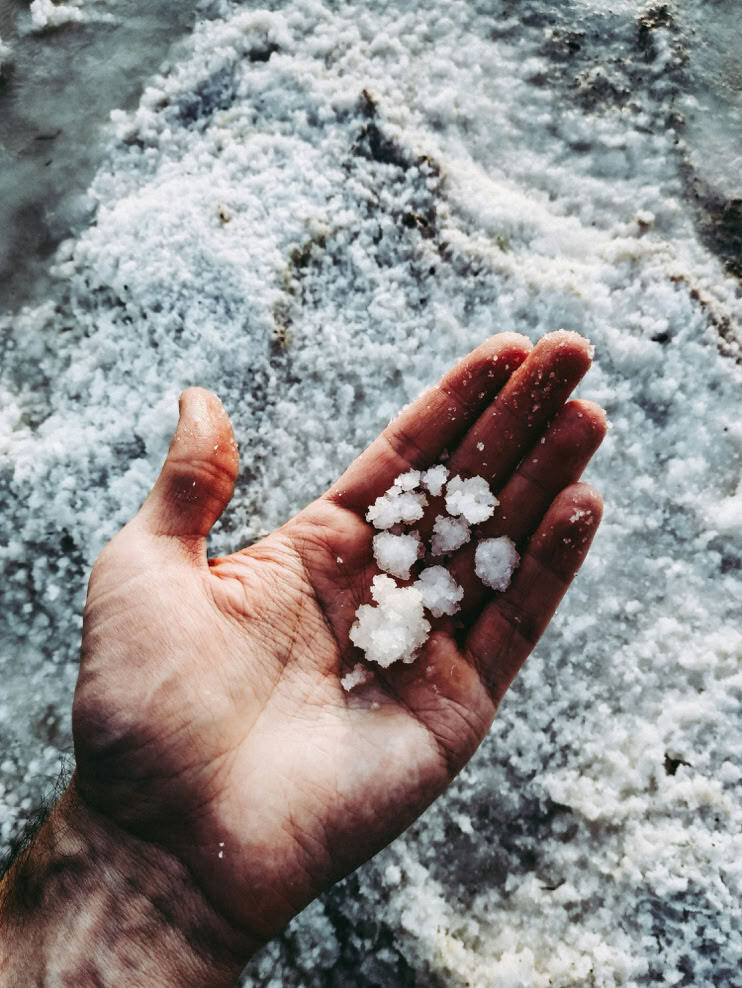 Una mano che raccoglie cristalli di sale marino