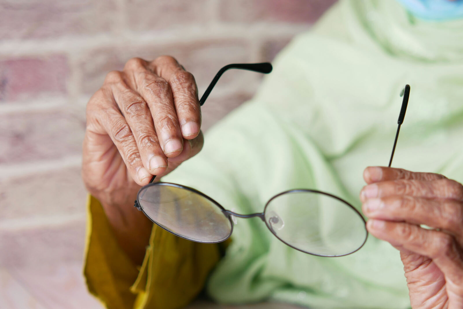 Elderly hands holding a pair of glasses